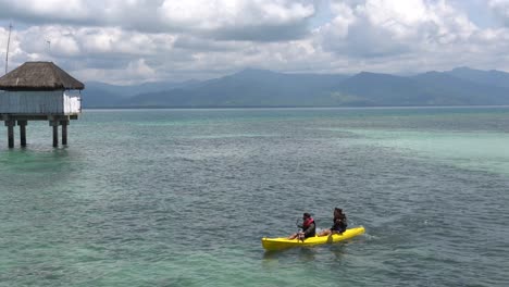 Tourists-Kayaking-At-The-Tropical-Blue-Ocean-Near-The-Cottages-In-Dos-Palmas-Island-Resort-And-Spa-In-Honda-Bay,-Puerto-Princesa,-Palawan,-Philippines