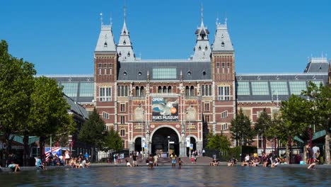 Timelapse-of-people-playing-in-water-and-walking-in-front-of-the-Rijksmuseum-in-Amsterdam,-the-Netherlands
