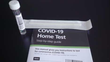 Right-to-left-pan-of-Covid-19-Coronavirus-home-test-kit-with-guide,-test-tube-and-cotton-q-tip