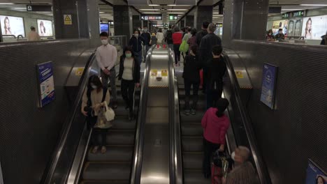 Corona-Virus-Pandemic,-Local-Commuters-using-a-Hong-Kong-underground-MTR-escalator-wearing-protective-face-masks