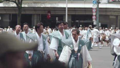 Japanische-Männer-In-Traditionellen-Kostümen-Gehen-Auf-Der-Straße-Während-Der-Yamaboko-Junko-Prozessionen-Mit-Festwagen-Beim-Gion-Matsuri-Festival-In-Kyoto,-Japan