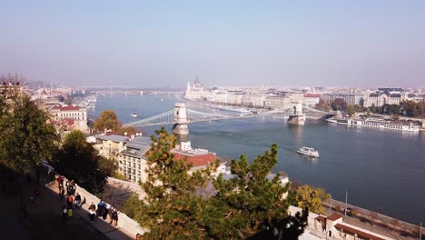 Static-shot-of-Budapest-Chain-bridge-from-a-great-distance-with-boats-on-Danube-river