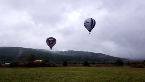 Hot-air-balloons-launching-into-the-skies-of-an-early-overcast-morning-during-an-event-in-Campu-Cetatii,-Romania