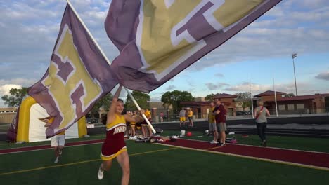 Cheerleaders-run-with-flags-before-a-high-school-football-game
