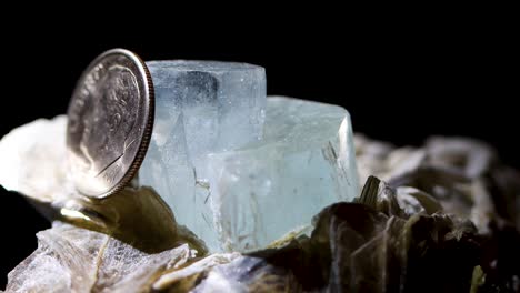 A-tight-detail-shot-of-an-aquamarine-crystal-in-a-muscovite-matrix-using-a-dime-as-a-reference-for-size
