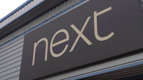 Next-retail-clothes-store-in-the-UK-panning-shot-of-sign