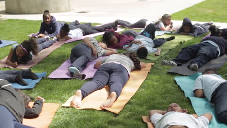Estudiantes-De-Primaria-Haciendo-Yoga-En-La-Hierba-En-La-Escuela,-Durmiendo-Y-Meditando,-Cámara-Lenta