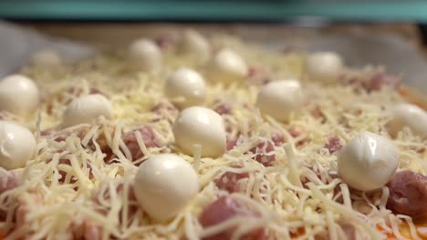 Selective-focus-small-balls-of-mozzarella-cheese-and-more-ingredients-on-homemade-pizza