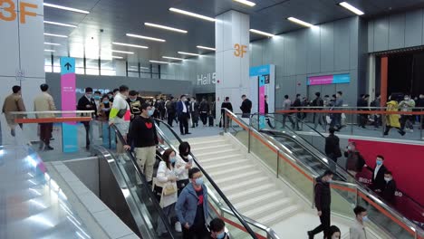 Time-lapse-of-endless-line-of-visitors-wearing-masks-and-taking-escalator-in-the-exhibition-hall-at-kitchen-design-exhibition-in-China,-during-COVID-19-pandemic