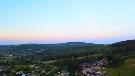 Aerial-view-over-a-village,-in-the-Carpathian-Mountains,-colorful-dusk-sky,-Ukraine---dolly,-drone-shot