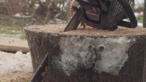 Parallax-shot-of-a-chainsaw-cutting-a-piece-of-wood-on-a-cloudy-day