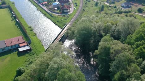 Train-Bridge-and-River-Sun-Reflection,-Lush-Summer-Scene-in-Europe,-Aerial-Top