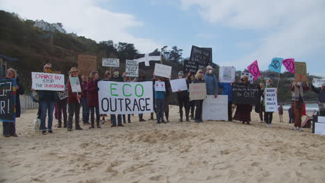 Protesters-closely-stand-united-together-on-beach-front-of-Carbis-Bay-Hotel,-Cornwall