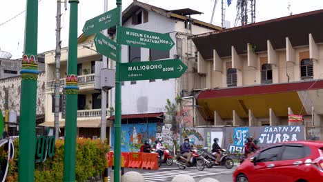 Street-names-on-guidepost,-rush-hour-car-and-motorcycle-traffic,-Indonesia