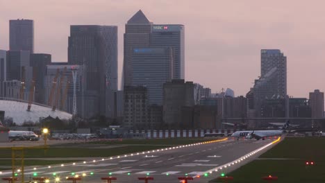 Small-LOT-aircraft-turning-on-runway-at-London-City-airport-evening-canary-wharf-in-background