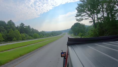 POV-from-roof-of-vehicle-driving-on-interstate-through-southern-Illinois-past-wooded-landscapes