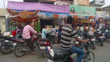 Gente-Comprando-En-El-Mercado-Callejero-Con-Motos-Estacionadas-A-Lo-Largo-De-La-Carretera-Durante-Un-Pase-De-Conducción-En-Agra,-India