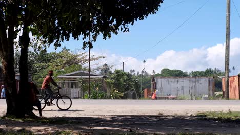 A-man-riding-a-bicycle-and-everyday-traffic-in-Buka-town-on-tropical-island-Autonomous-Region-of-Bougainville,-Papua-New-Guinea