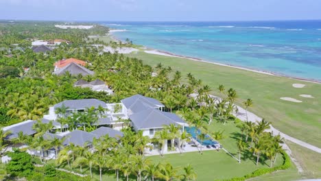 Drone-shot-of-tropical-landscape-with-luxury-hotel-and-golf-course-beside-beach-of-Caribbean-Sea---Beautiful-coastline-of-Dominican-Republic-during-sunlight