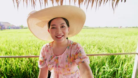 Schöne-Junge-Asiatische-Frau-Mit-Hut-Im-Reisfeld,-Die-Einen-Videoanruf-Tätigt