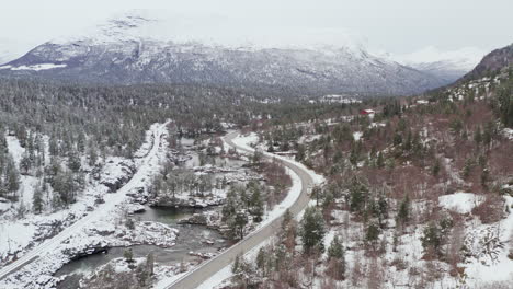 Luftaufnahme-Von-Fahrzeugen,-Die-Im-Winter-Durch-Verschneite-Berge-Und-Wälder-In-Dovre,-Kreis-Innlandet,-Norwegen-Fahren