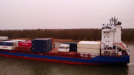 Aerial-Along-Port-Side-Of-JSP-Carla-Cargo-Ship-Travelling-On-Oude-Maas-On-Overcast-Day-In-Puttershoek