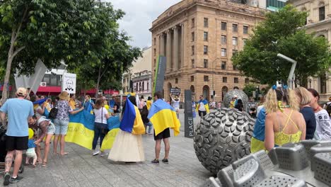 Big-group-of-people-gathered-at-Brisbane-Square-holding-Ukrainian-Flag,-banners-and-placard-to-show-support-for-the-Ukrainian-people-in-the-war-zone-protecting-their-home-country-against-Russian-force