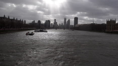Sun-beams-and-dark-clouds-move-fast-over-a-very-choppy-River-Thames-and-distant-skyscrapers-and-construction-cranes-during-Storm-Eunice