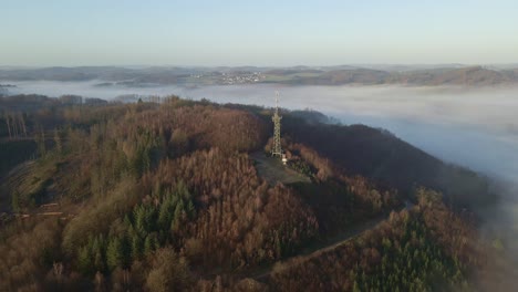 Observation-tower-with-transmission-mast-sitting-on-the-edge-of-a-steep-hill-in-Morsbach,-Germany-during-sunrise