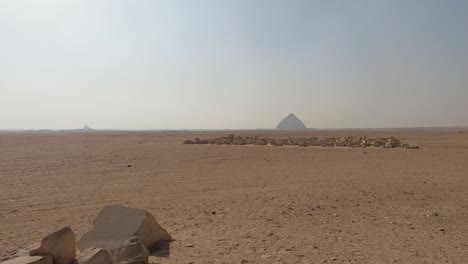 Bent-Pyramid-At-Royal-Necropolis-Of-Dahshur,-near-Cairo,-Seen-In-The-Distance-Through-Bright-Desert-Air