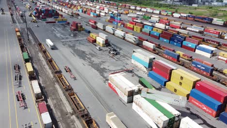 Aerial-drone-shot-flying-over-a-logistics-terminal-where-shipping-containers-full-of-freight-and-goods-are-prepared-for-distribution-using-the-national-railway,-Toronto,-Canada