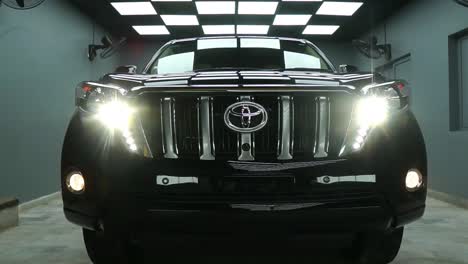Front-View-Of-Black-Toyota-Land-Cruiser-Prado-With-Headlights-Switched-On