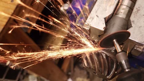 Person-using-angle-grinder-to-fix-steel-gear-part-of-vehicle,-close-up-view