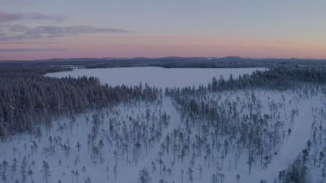 Aerial-view-pull-away-from-sunrise-above-frozen-Norbotten-woodland-Lapland-winter-landscape