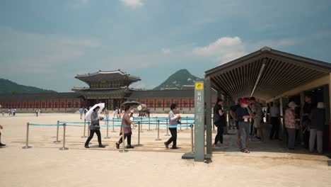 A-crowd-of-people-comes-up-to-Gyeongbokgung-Palace-Ticket-Box-to-buy-entrance-tickets-with-Heungnyemun-Gate-and-Bukhansan-mount-peak-in-the-background