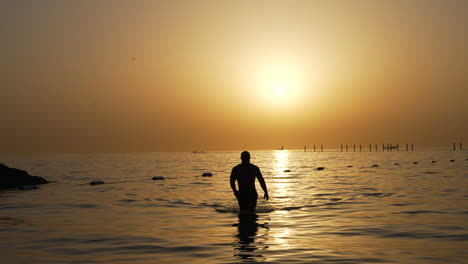 Mann,-Der-Im-Sonnenuntergang-Am-Persischen-Golf-Von-Dubai-Aus-Dem-Meer-Geht
