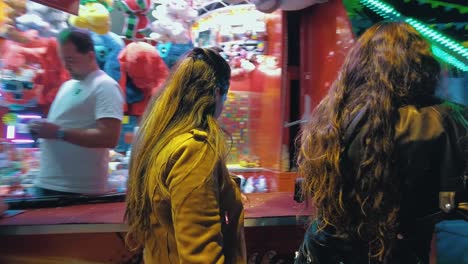 two-pretty-girls-standing-at-a-shoot-stall-at-the-fun-fair-playing-a-game