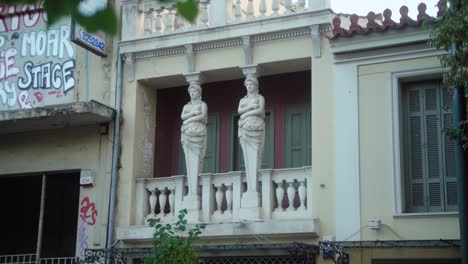 Nahaufnahme-Zweier-Statuen-Auf-Einem-Balkon,-Umgeben-Von-Graffiti-An-Den-Wänden-In-Athen,-Griechenland