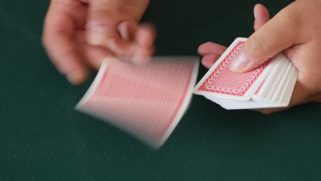 Close-up-of-a-casino-dealer's-hands-as-he-deals-playing-cards-and-then-fans-out-the-cards-on-the-table