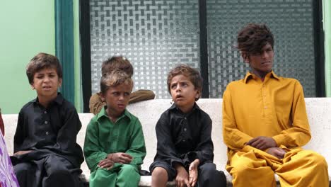 Numerous-distraught-looking-children-sitting-in-the-bench-at-the-side-of-the-road-in-Sindh,-Pakistan
