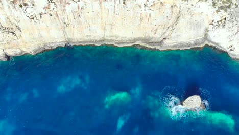 Drone-Disparó-Sobre-Rocas-Y-Acantilados-Con-Olas-Golpeando-Una-Pequeña-Roca-En-El-Mar-Mediterráneo-De-Malta-4