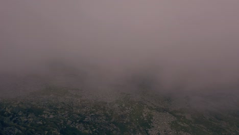 Wide-shot-of-aerial-drone-view-of-Retezat-Mountains,-Romania-seen-through-fog