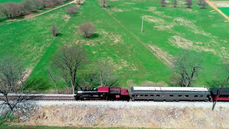 Steam-Train-Puffing-along-Amish-FarmLand-on-a-Sunny-Summer-Day-as-seen-by-a-Drone