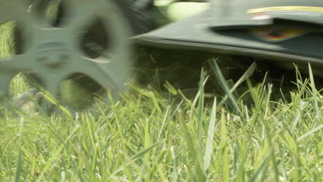 Close-up-of-man-walking-by-mowing-grass-with-electric-lawnmower