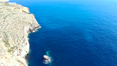 Drone-shot-over-rocks-and-Cliffs-with-wave-hitting-a-small-rock-in-the-Mediterranean-sea-of-Malta-2