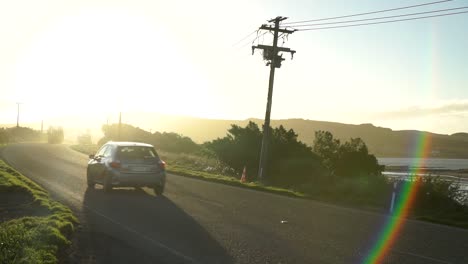 Sunset,-road,-passing-cars-and-ocean-sea-coast-in-Bluff,-New-Zealand