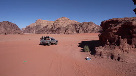 Un-Camión-Con-Turistas-En-El-Maletero-Se-Aleja-Por-La-Arena-Hacia-Las-Dunas-Del-Desierto-De-Wadi-Rum