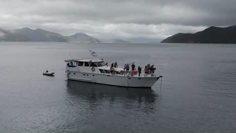SLOWMO---People-fishing-off-anchored-cruise-boat-in-bay-in-Marlborough-Sounds,-New-Zealand