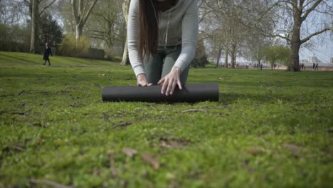 Kaukasische-Frau-Rollt-Ihre-Yogamatte-In-Einem-Park-Aus