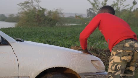 Close-shot-of-young-African-man-washing-a-car-with-water-from-Lake-Victoria